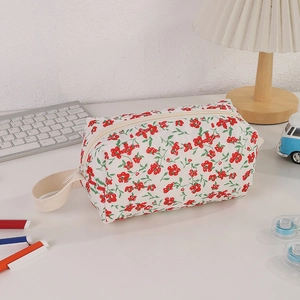 Close-up of quilted floral pencil case with zipper closure and side handle on desk