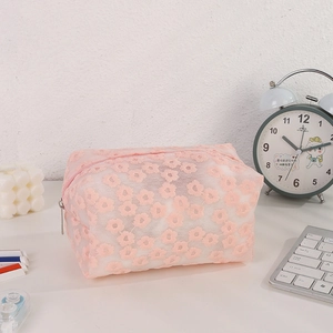 Close-up of pink lace daisy embroidery and silver zipper on a mesh cosmetic storage bag