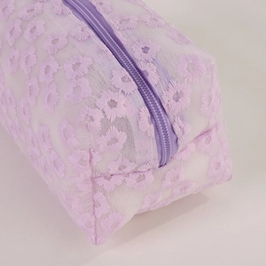 Close-up of lavender floral embroidery on a translucent mesh makeup bag with zipper