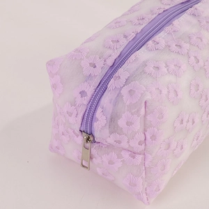 Detail of purple mesh makeup bag featuring floral embroidery and silver zipper puller