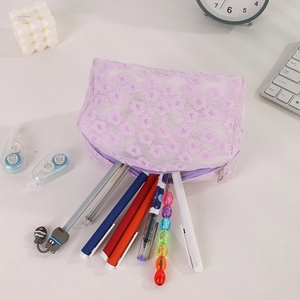 Detail view of purple daisy lace mesh pouch with stationery tools on a white desk