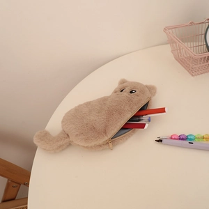 Detail view of a fluffy cat-shaped pencil case with a smooth zipper on a white desk