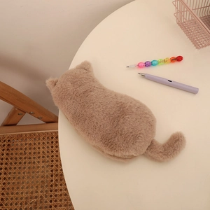 Close-up of cute brown plush cat-shaped stationery pouch on a white round desk