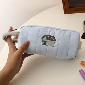 Detailed view of the quilted light blue fabric pencil case with house embroidery