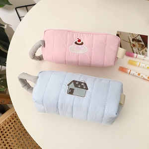 Close-up of quilted fabric pencil cases with embroidery and side carry handles