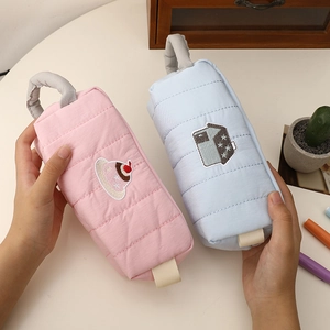 Close-up of quilted blue and pink pencil bags with cute embroidery and top handles
