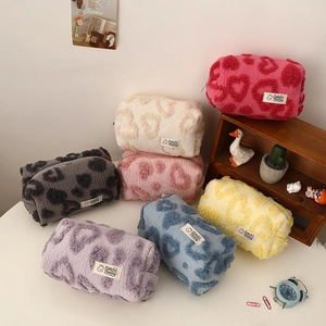 Plush heart patterned cosmetic bags in various colors on a cozy shelf arrangement