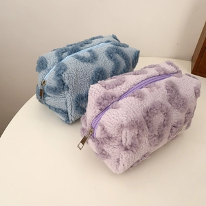 Detail of plush leopard print makeup bags in blue and lilac with a soft wool-like texture