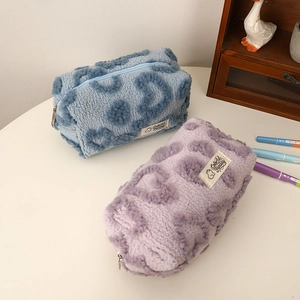 Close-up of plush heart leopard makeup bags in blue and purple on a white desk