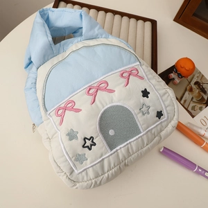 Detailed close-up of quilted storage bag with house embroidery and blue handles