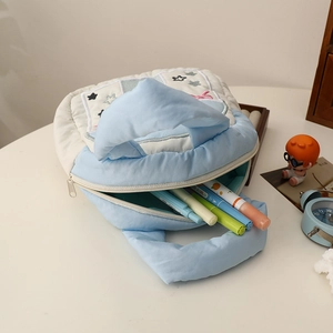 Quilted blue storage pouch with star embroidery shown with markers on a white desk