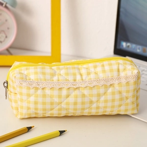 Detail of yellow plaid pencil case with diamond quilting and lace trim on desk