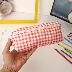 Detail of red checkered pencil case with lace trim and quilted cotton texture in hand