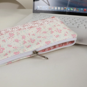 Dettaglio dell'astuccio floreale con pizzo e fodera interna a quadretti rosa