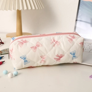 Gros plan sur la trousse matelassée avec motifs de nœuds roses et fermeture éclair rose