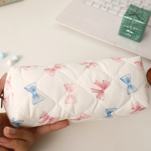 Trousse matelassée avec imprimés nœuds roses tenue dans un décor de bureau d'étude