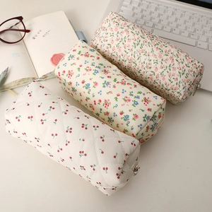 Trousses en tissu matelassé avec motifs floraux et cerises sur un bureau