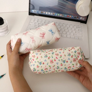 Trousses à crayons matelassées avec nœuds et motifs floraux sur un bureau moderne