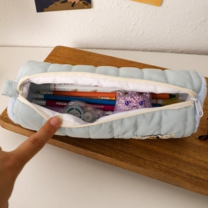 Dettaglio dell'astuccio trapuntato azzurro con chiusura a zip e interno capiente