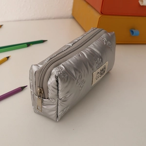 Detailed close-up of silver quilted pencil case with metallic finish and bow patterns