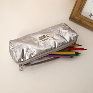 Detail of silver metallic pencil case with 3D bow texture and colorful stationery