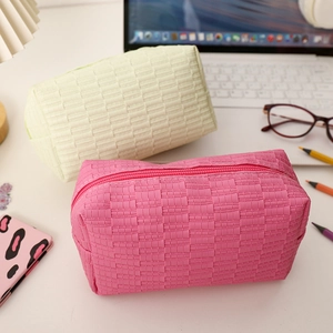 Close-up of pink and green cosmetic bags with quilted texture and zipper on the desk