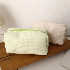 Detail of woven texture storage bags in green and beige on a wooden board