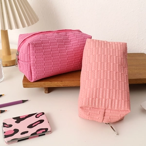 Close-up of pink textured quilted cosmetic bags with premium metallic zippers on table