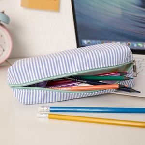 Detailed storage capacity view of blue striped seersucker pencil case with pencils
