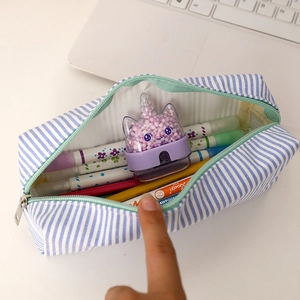 Spacious seersucker pencil case with blue stripes holding colorful pens and sharpener