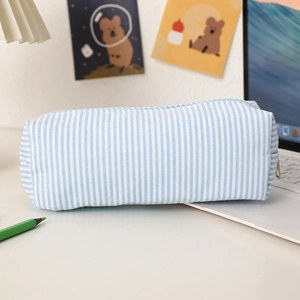 Detailed view of seersucker pencil case with blue stripes and zipper on white desk