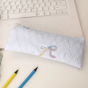 Detail of light blue pencil case featuring quilted texture and colorful bow embroidery