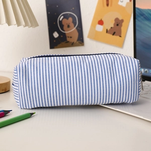 Seersucker pencil case with blue and white stripes on a desk with cozy stationery decor