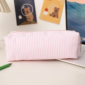 Pink striped seersucker pencil case on a cozy desk with laptop and cute stationery
