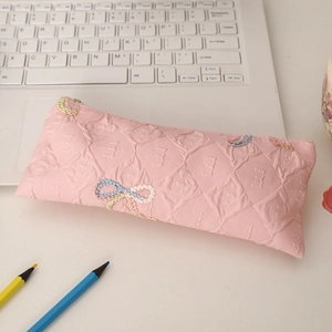 Detail of pink quilted pencil case with bow embroidery and metal zipper texture