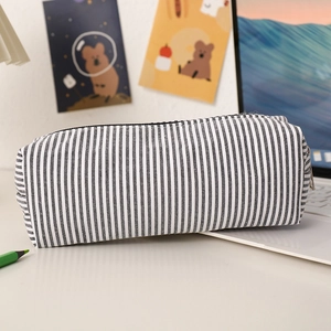 Seersucker striped pencil case on a desk with a laptop and cartoon art background
