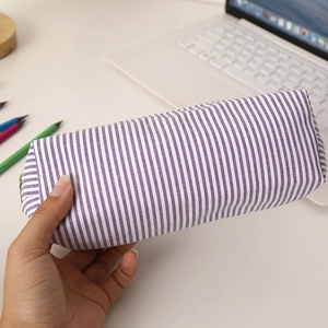 Handheld view of a large purple striped seersucker pencil case on a desktop