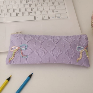 Close-up of lavender quilted pencil case with detailed 3D embroidered bow and top zipper