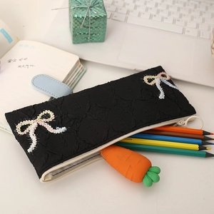 Detail of black quilted pencil case with colorful bow embroidery and open zipper