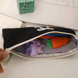 Detail of black jacquard pencil case with embroidery and spacious interior for stationery