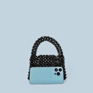 Detail of black acrylic beaded handbag next to a smartphone for size comparison