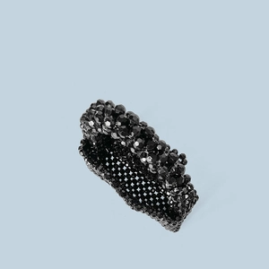 Detailed macro view of black faceted acrylic beads and handmade woven texture on the bag