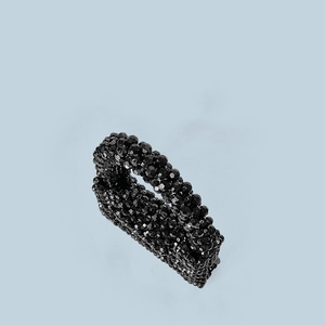 Macro shot of high-gloss black acrylic beads on a handmade woven mini handbag