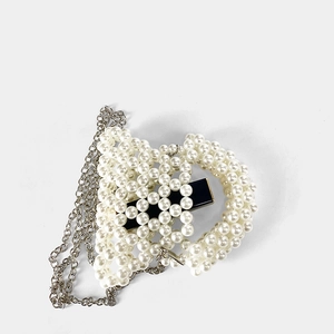 Détail du mini sac perlé en forme de cœur avec chaîne argentée et texture de perles