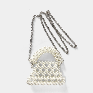 Détail des perles blanches faites main et de la chaîne argentée sur le mini sac trapèze