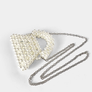 Détail d'un mini sac à main trapèze en perles blanches avec une chaîne en métal argenté