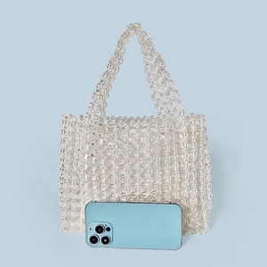 Handmade clear acrylic beaded handbag shown with phone for size reference and scale