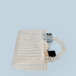 Detailed interior of a clear acrylic beaded handbag showing storage for phone and perfume