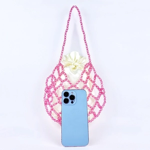 Pink beaded woven bag with satin drawstring pouch and smartphone for size reference