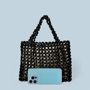 Close-up of black beaded handbag showing woven grid pattern and phone size reference